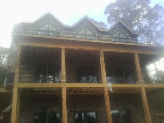 Dormers and porch framing on a large log home under construction — Roof Coating work by our crew in Hallstead