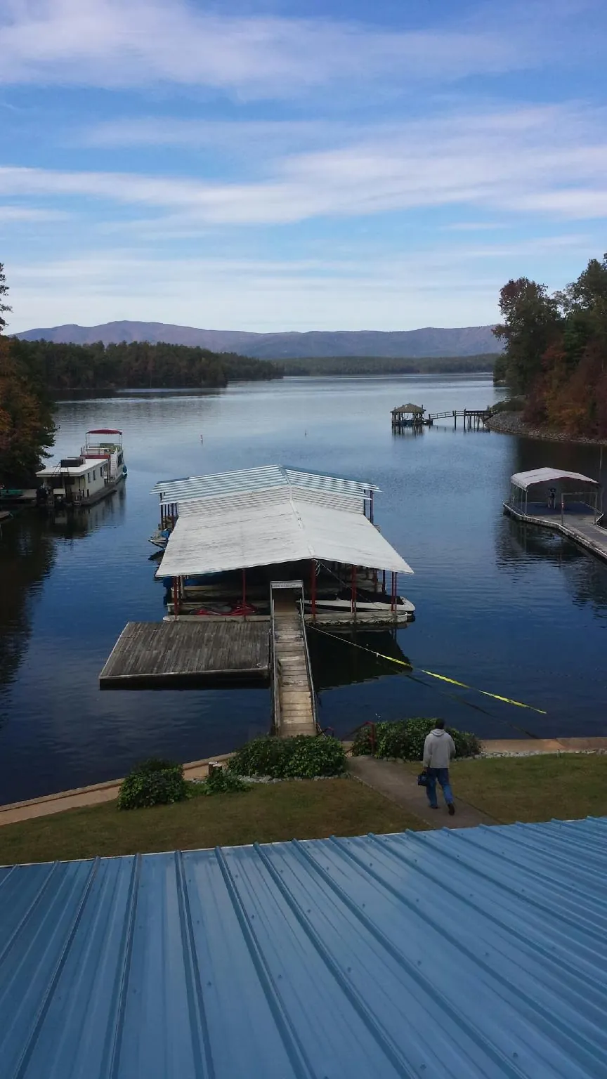 View across a lake from a newly installed blue metal roof in Hallstead