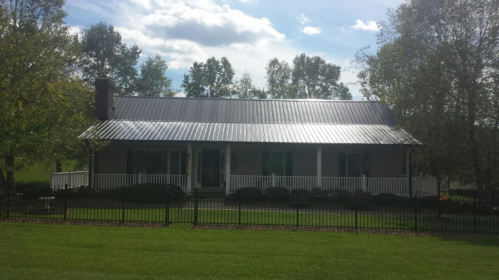 Gray metal roof on a brick ranch with a full width front porch — Gutter Guard Installation work by our crew in Hallstead