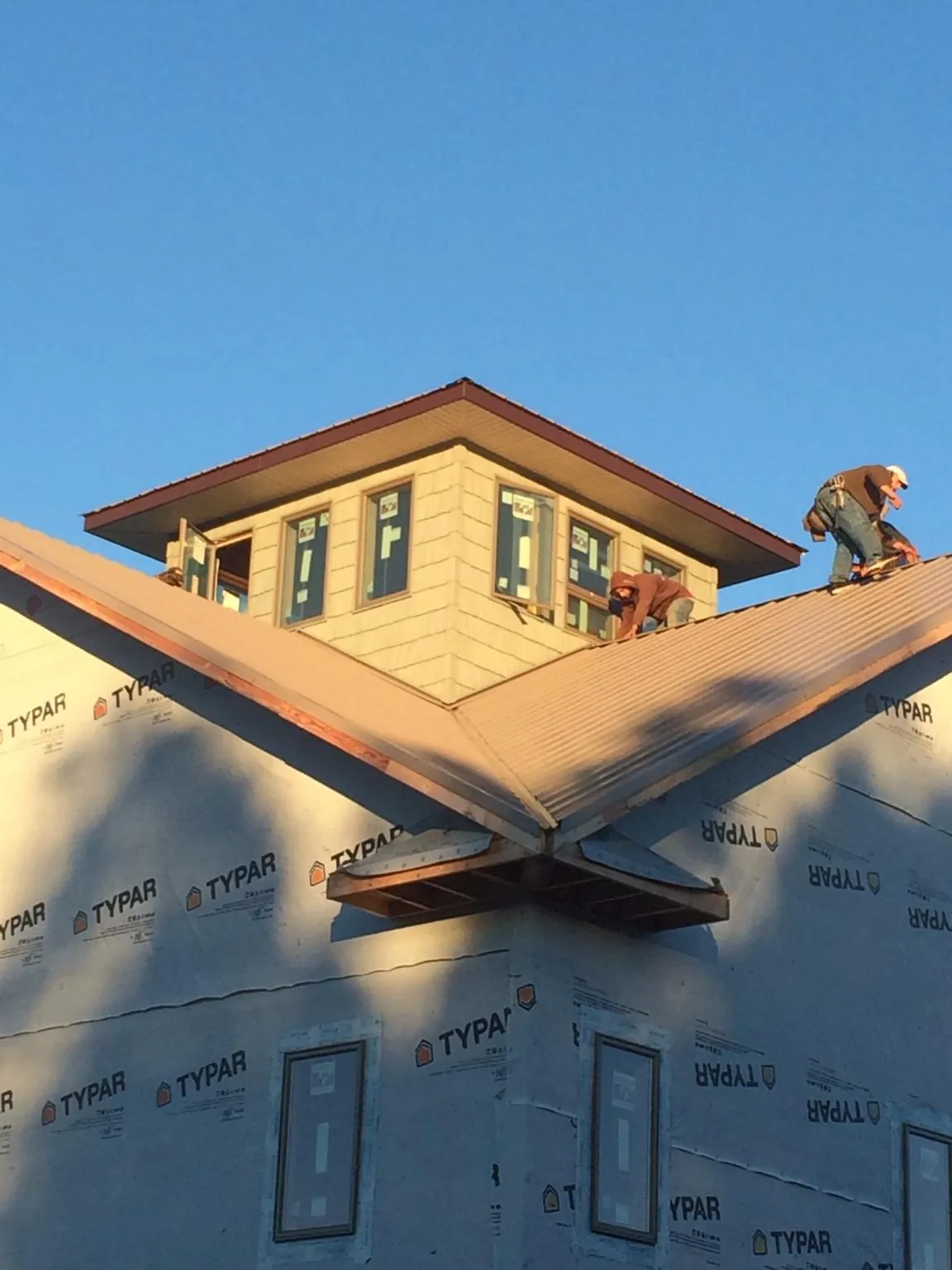 Roofers working around a rooftop cupola on a new metal roof at sunset — Roof Waterproofing in Hallstead by Roofing Brothers